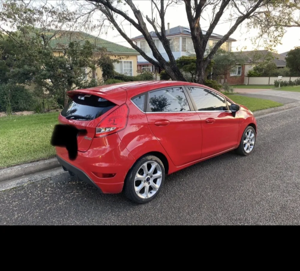 Red Ford Fiesta hatchback parked on a suburban street